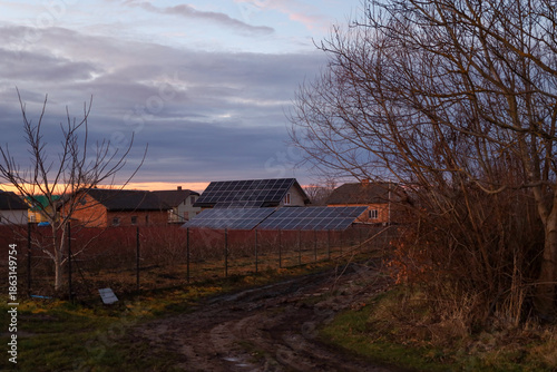 Fotografie Modern solar panels are installed on the roof and in the yard of a private house in a rural area against an evening sky