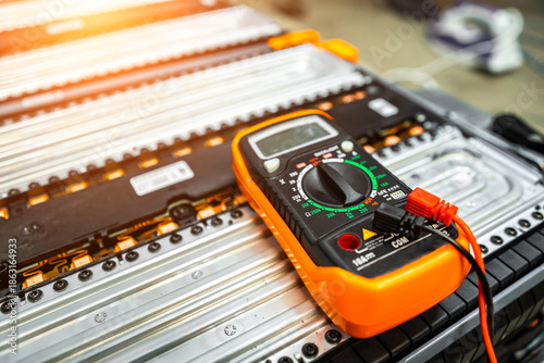 Photos the multimeter is lying on the battery of an electric car on a blurry background