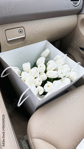 there is a box with a bouquet of white tulips in the car's interior.