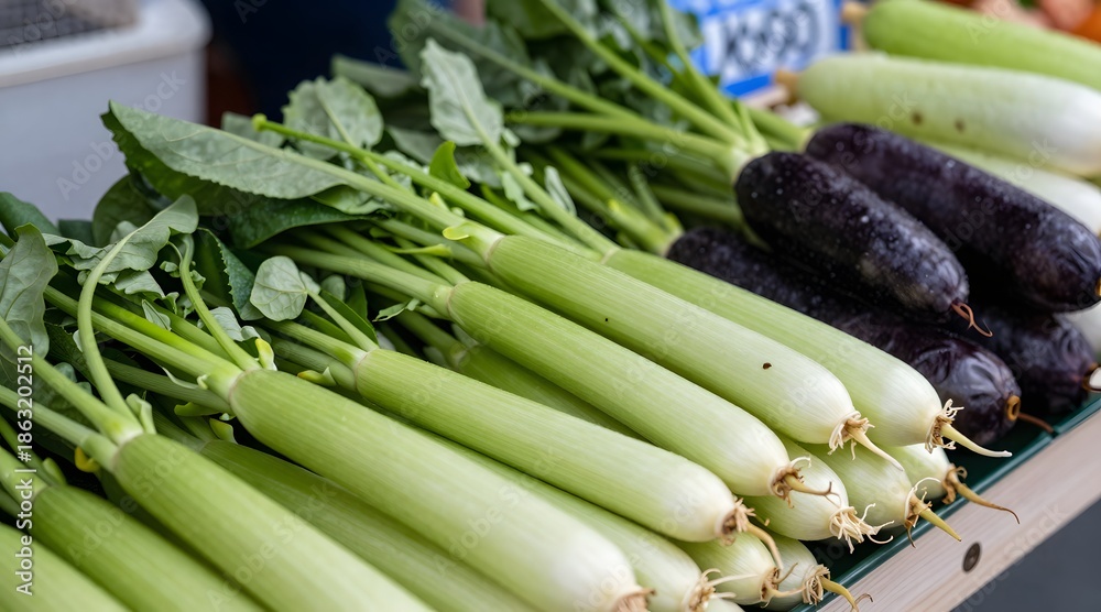 Obraz premium Close-up of fresh produce at a farmer's market showing taro stems, gai lan and zucchini