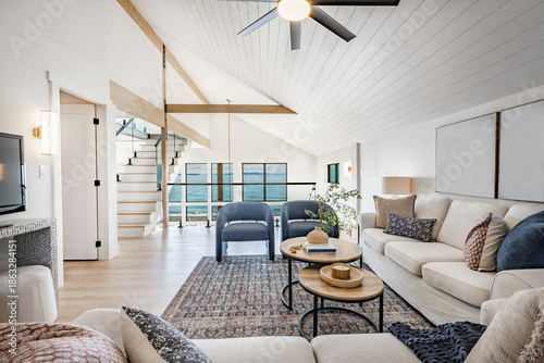 spacious interior living room floor to ceiling windows looking toward pacific ocean view bright blue sky seaside waterfront estate with comfortable furniture staged professionally decorated designer