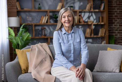 Fotografija Senior woman with gray hair smiling confidently, sitting comfortably on a sofa i