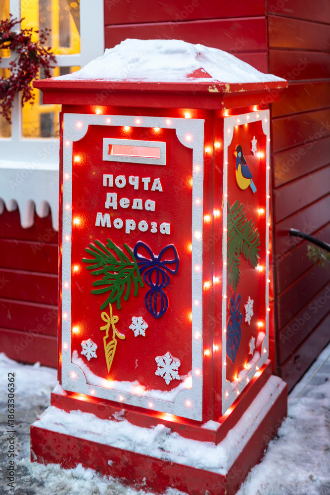 Φωτογραφία Bright red festive postbox with glowing edges, blue bird motif, evergreen bows, and snow accents, part of a holiday installation in Moscow, Russia