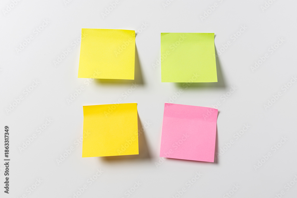 Fototapeta premium four blank colorful sticky notes on white wall. Template mock up
