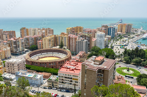 Panoramic cityscape of Malaga from Mirador de Gibralfaro; Plaza de Toros bullring and Mediterranean Sea. Andalusia Spain travel destination skyline. Urban architecture coast view port lighthouse sun.