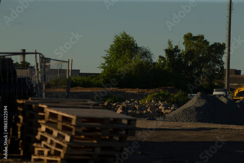 Φωτογραφία dusk construction yard with stacked pallets, materials staged for contractor pic