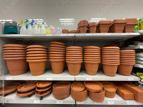 Shelves with stacked terracotta flower pots, trays and planters in a garden store. Gardening supplies display with clay pots for plants, seedlings and home garden use. Retail, horticulture and DIY con