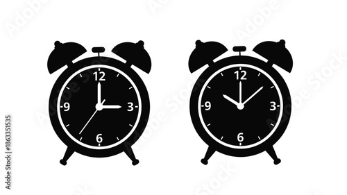Two black alarm clocks displaying different times a striking silhouette