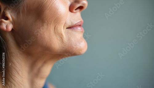 Close-up side profile of an elderly woman neck and jaw showing prominent wrinkles and skin texture. Aging skin detail, natural skin tone, subtle smile lines.