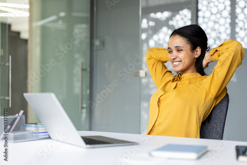 Bild auf Leinwand Young professional woman smiling and relaxing at her desk, feeling satisfied and