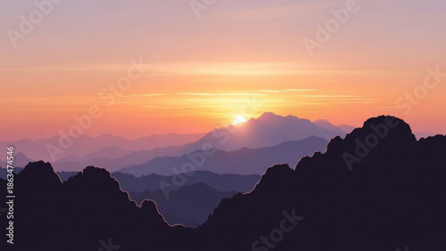 Sunset over mountain range with silhouette of rocky peaks in foreground at dusk with orange with landscape