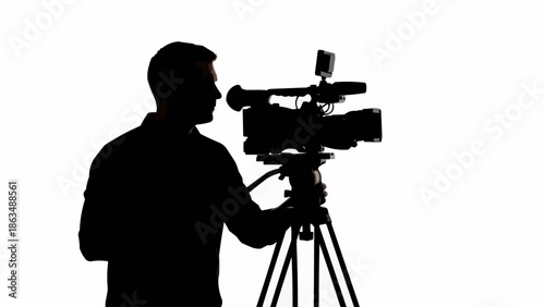 Silhouette of a cameraman operating a professional video camera on a tripod.