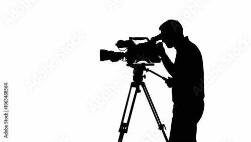 Silhouette of a cameraman operating a professional video camera on a tripod.
