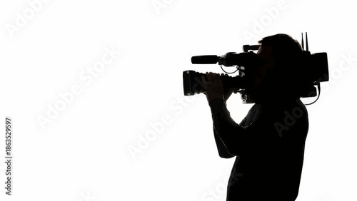 Silhouette of a videographer holding a professional video camera.