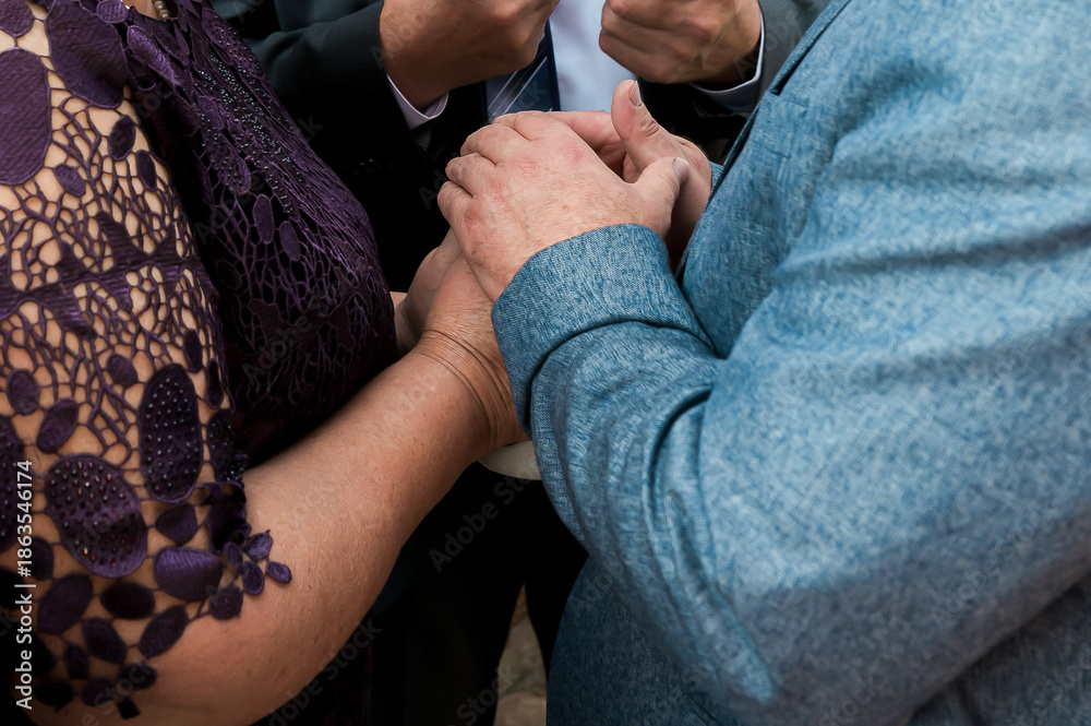 Fototapeta premium Close-up of family hands joined during a wedding ceremony, symbolizing love, unity, support, and emotional connection at a meaningful celebration.