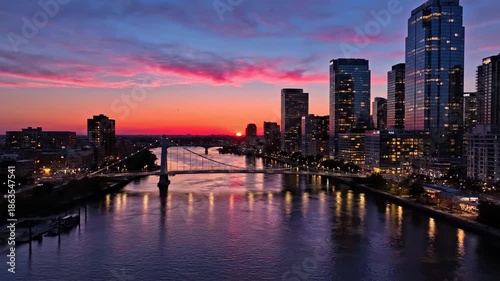 Wallpaper Mural A cityscape at sunset with river, bridge, high-rise buildings, and fiery colorful sky Torontodigital.ca