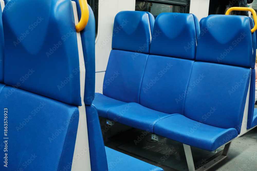 Obraz premium Blue vinyl seats in row, with yellow grab handle, inside an empty public transportation coach