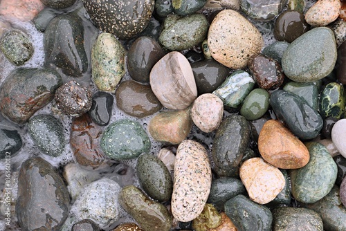 Background, texture of sea pebbles in the sea foam of the surf