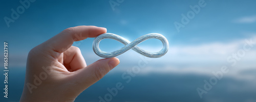 Infinity symbol steel wire human hand blue sky calm water minimal concept freedom future vision abstract shape coastal horizon Serene hand holding metal infinity symbol against blue sky and calm