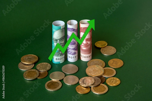 Concept of minimum wage increase using Colombian peso bills and coins and an upward arrow. Living minimum wage.