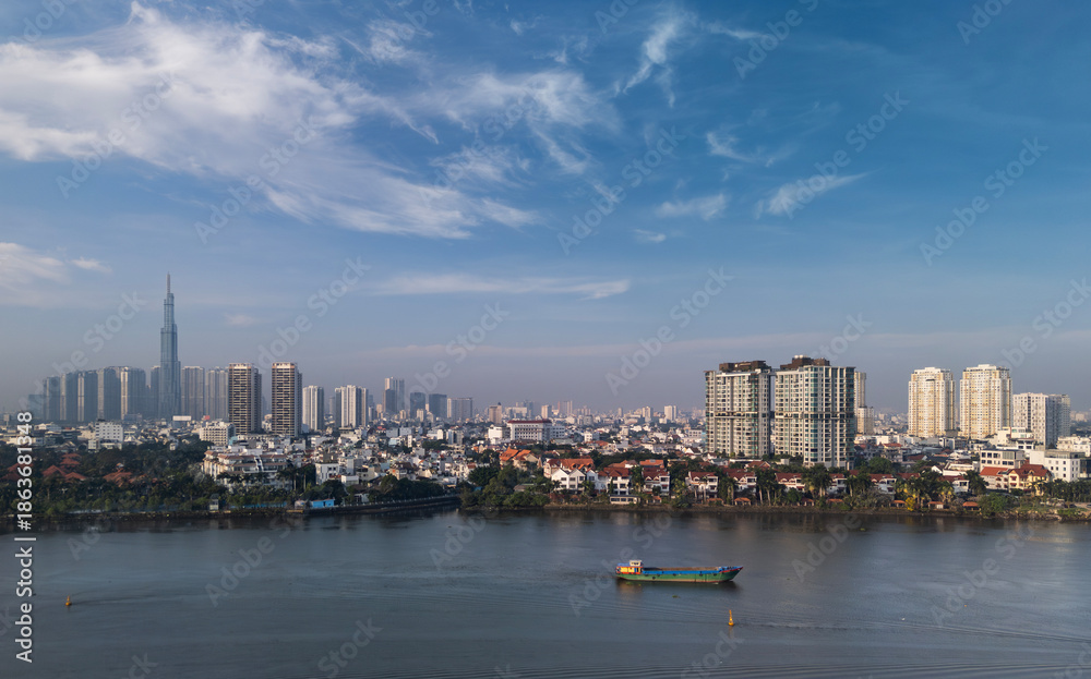 Fototapeta premium Aerial view of Ho Chi Minh City Skyline and Saigon River waterfront from Thao Dien in early morning on sunny clear day.