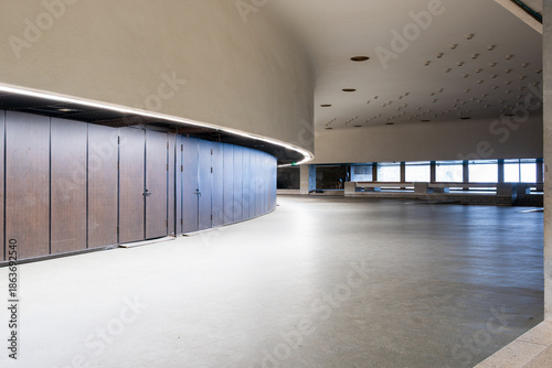 Empty Modern Interior of Abandoned City Hall with Curved Wooden Concert Hall Entry Doors, Concrete Floors, Window Wall Showing Contemporary Architecture in Deserted Government Space