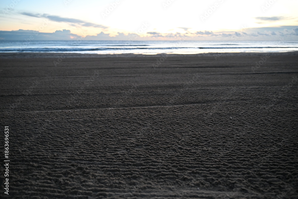 Obraz premium A corduroy-textured beach in the morning with empty space and visible beach shower hydrants 