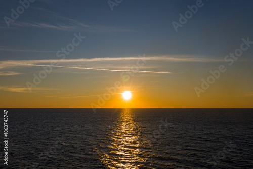 Bilde på lerret The sun sets low on the horizon, casting a warm golden reflection across the tranquil surface of the Adriatic Sea