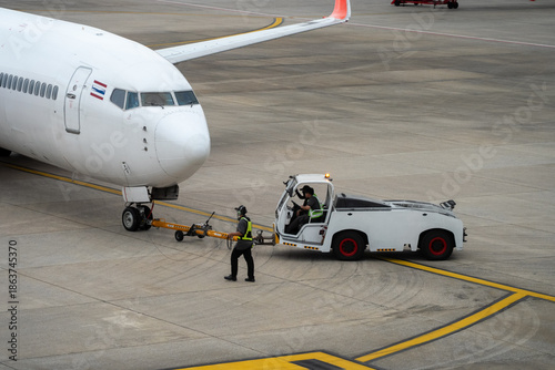 Photography A white airplane is being towed by a white truck