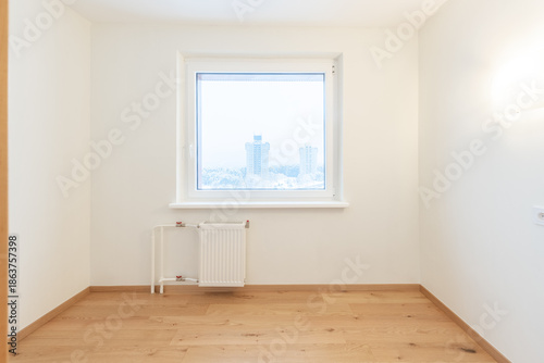 Bright Empty Room With Wooden Flooring and Large Window Overlooking Urban Scenery