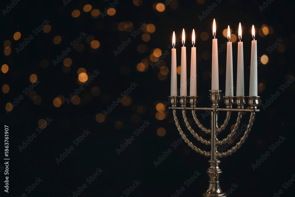 Fototapeta premium Hanukkah menorah with glowing candles and golden bokeh lights