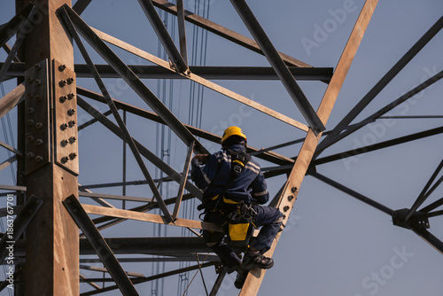 Electrical engineers climb high voltage power poles for maintenance.