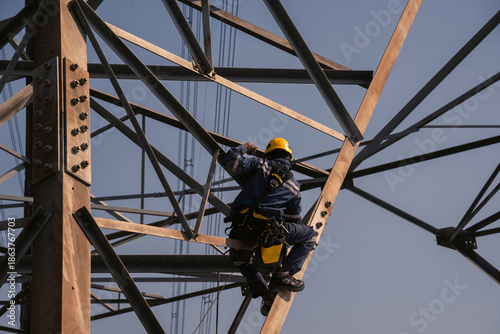 Electrical engineers climb high voltage power poles for maintenance.