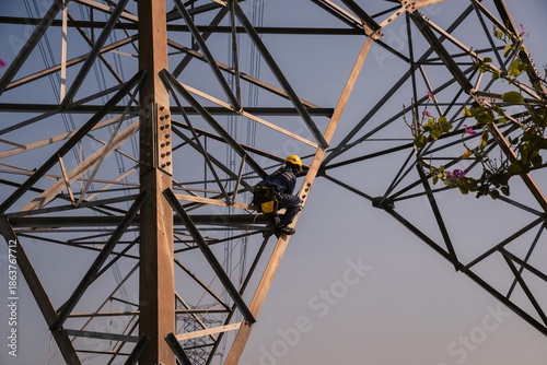 Electrical engineers climb high voltage power poles for maintenance.