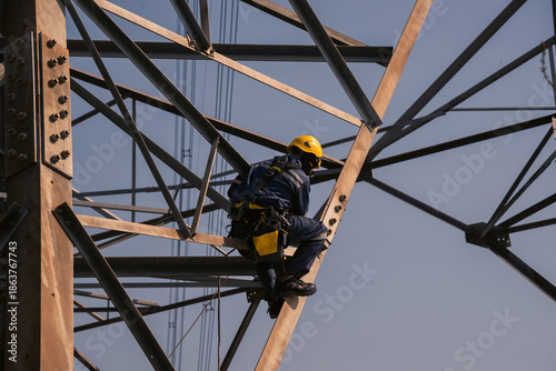Electrical engineers climb high voltage power poles for maintenance.