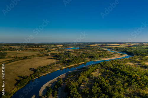 Canvastavla Aerial view of the Loire river winding through sunlit agricultural fields and dense green forests in the Nievre region