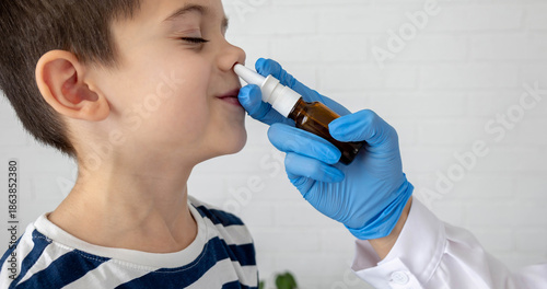Foto Doctor using nasal spray to treat runny nose in a little boy