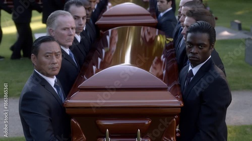 A solemn group of individuals carrying a casket at a funeral, showing respect and mourning. They are dressed in formal attire Stock Video