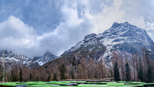 Bild auf Leinwand A breathtaking winter mountain landscape covered in deep snow, with dramatic clouds rolling over rugged alpine peaks under a bright blue sky, creating a serene and powerful natural atmosphere