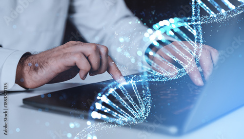 Valokuva Hands typing on laptop with glowing DNA strand hologram overlay on blue background, symbolizing biotechnology and digital genetics concept