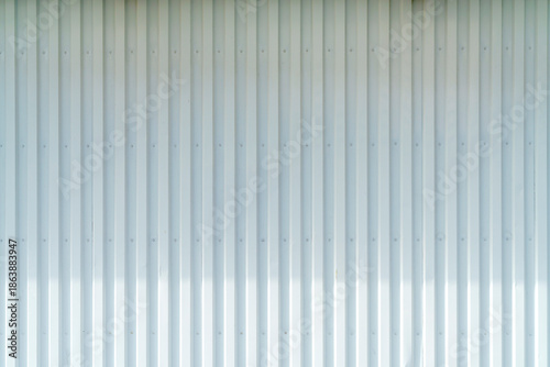 White corrugated metal wall background texture with vertical lines and rivets. Clean industrial surface for construction or architectural backdrop. Frontal view with bright natural light.