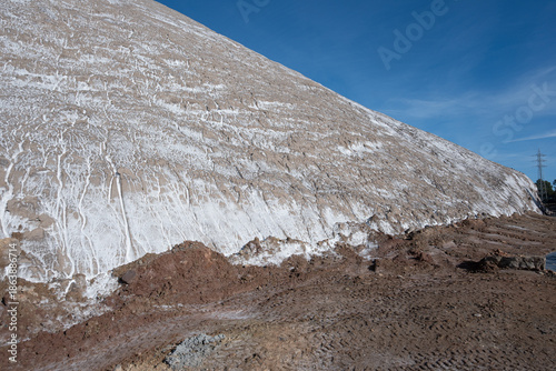 Vast brown slope marked by striking white mineral streaks, illustrating natural erosion and industrial transformation. 