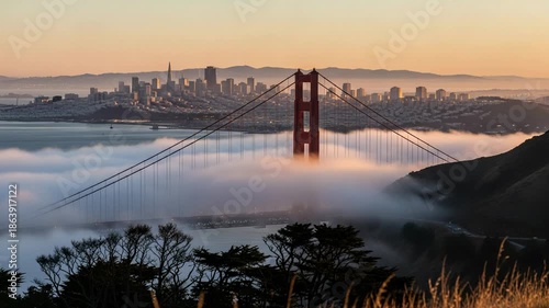 Golden Gate Bridge shrouded in fog at sunrise with San Francisco skyline