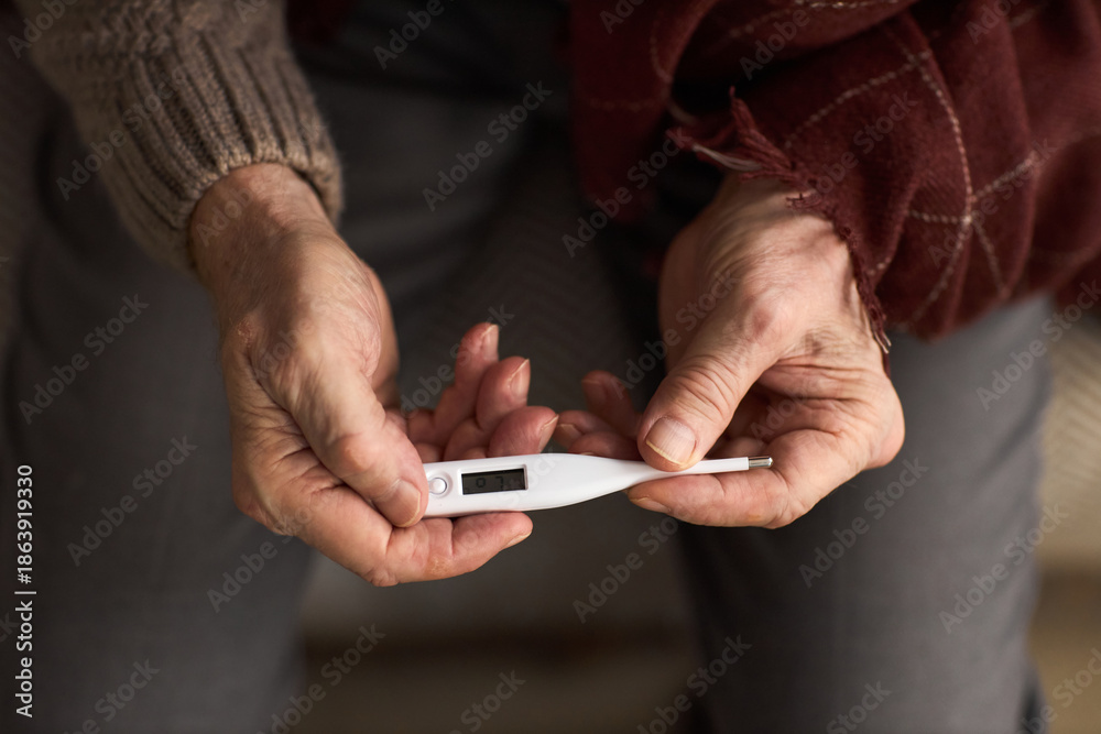 custom made wallpaper toronto digitalSenior Caucasian man holding digital thermometer with both hands, sitting at home, showing close up of wrinkled hands and medical device, focusing on health monitoring