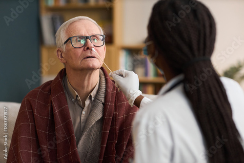 Quadro em tela Caucasian senior man sitting while Black woman healthcare worker performing nasa