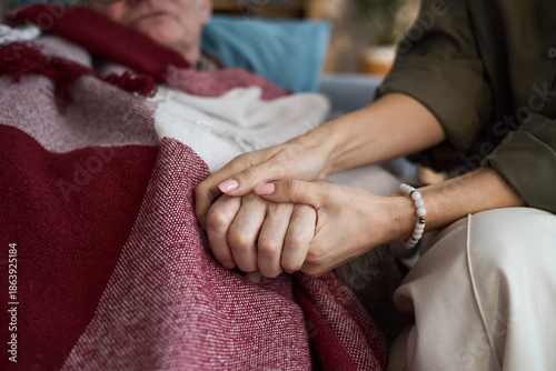 Schilderij op canvas Middle aged Caucasian woman holding hand of senior Caucasian man lying under bla