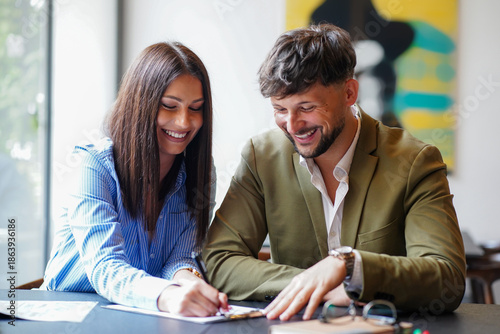 Φωτογραφία Two people working together at a table in a coffee shop while smiling and sharin