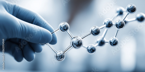 Gloved scientist hand holding metallic molecular structure representing peptides, chemistry and advanced biomedical research in a modern laboratory.