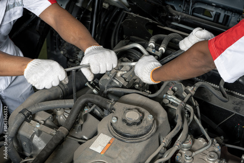 Photos Two professional mechanics hands repairing a heavy duty truck engine in a service center
Close up of mechanics team wearing gloves using wrenches to fix and maintain a large vehicle engine
