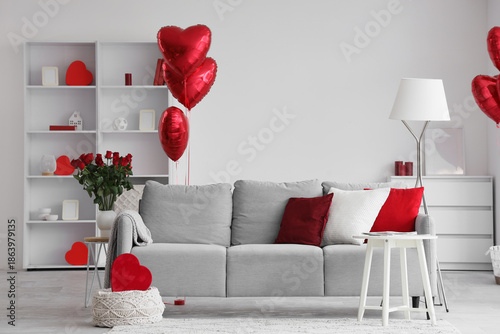 Interior of light living room decorated for Valentine's Day with sofa, lamp and balloons